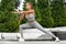 Fitness woman stretching and warming up for her training outdoors. Active girl doing lunges exercises