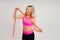 Fitness woman with tape measure showing her waist on studio background