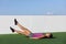 Fitness woman training abs workout doing scissor lifts leg raise or flutter kicks exercise out outdoor grass floor at