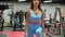 Fitness woman training squat lunges with dumbbells in gym club. Sportswoman squatting with weight at fitness
