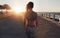 Fitness woman walking on a seaside promenade at sunset.