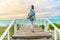 Fitness woman walking with yoga mat on beach