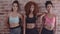 Fitness women standing against brick wall in gym