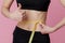 Fitness, workout, healthy lifestyle and diet concept - thin athletes women measure waist after exercise.