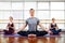 Fitness, yoga and healthy lifestyle concept - group of people doing lotus seal gesture and meditating in seated pose at