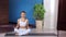 Fitness yoga woman sitting in lotus position practicing breathing rising up hands full shot