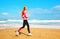 Fitness young woman is running summer along the beach