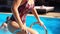 Fitted beautiful girl in wet swimsuit climbs out the swimming pool by ladder with handrails. Young woman crawl out of