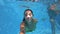 Fitted pretty woman in swimsuit diving under water in swimming pool, shooting herself on action camera. Mixed race girl