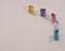 Five binder clips of different colors on a gray background as characters standing next to each other, selective focus