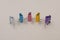 Five binder clips of different colors on a gray background as characters standing next to each other, selective focus