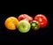 Five bright multicolored assorted tomatoes on a black background