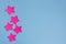 Five bright pink stars stickers on a blue background. Flat layout with copy space