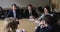 Five businesspeople negotiating sit at desk in boardroom