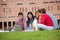 Five casual students sitting on the grass looking at laptop