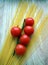 The five cherry tomatoes on the branch with spaghetti,wooden background