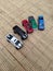 Five colorful double-cabin toy cars on a rattan mat