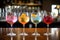 Five colorful gin tonic cocktails in wine glasses on bar