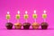 Five Cupcakes with burning candles over a pink background.