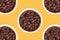 Five cups with coffee grains on a yellow background.