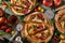 Five cutted tomatoes pizzas flat lay with tomato and fresh greens on shabby background