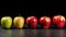 five different colorized apples standing in a line on a black table