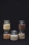 Five different types of cereals in jars on a black background. Porridge. Healthy food