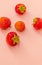 Five fresh homemade strawberry berries lie against a pink background