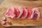 Five fresh raw lamb cutlet on a wooden cutting board