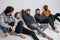 five friendly mixed race models in stylish casual clothes posing at camera sitting on floor