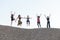 five girlfriends jumping together with joy on pebble hill