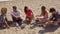 Five good looking friends sitting on a sandy beach