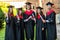 Five graduates posing in front of the university