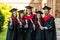 Five graduates posing in front of the university