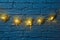 Five handcrafted wicker decorative hearts with lights hang on a decorative brick wall. Above and below there is a place