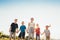 Five kids brothers and sisters teenagers and little kids walking on the green grass meadow with evening sunset background light