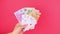 Five of a kind Poker Game cards in gambler hand with Euro money bills pink background. Lucky combination Aces Joker revealing 4K