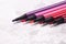 Five markers or pens in pink, purple, pink on a white background