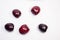 Five maroon dark red cherries isolated on a white background