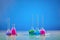 Five medical flasks with colorful chemical reagents. Testing kit and syringe against blue background. Coronavirus