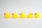 Five mini rubber ducks in a row. Two facing each other talking