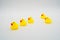 Five mini yellow rubber ducks in a row. One duck making their wa