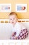 Five-months baby sits in white bed