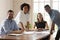 Five multiethnic businesspeople gather in boardroom smiling posing for camera