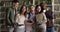 Five multiracial students holding textbooks posing in library