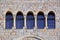 Five old windows with arches, columns and lattices on a stone wa