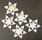 Five origami star snowflakes in white and gold foil paper, on a dark grey paper background