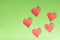 Five paper hearts on a green background