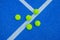 Five pickleball balls next to a blue court line, racket sports concept