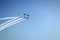 Five planes flying against the blue sky. One plane makes a barrel acrobatic figure around the others. Airshow at Chisinau Airport